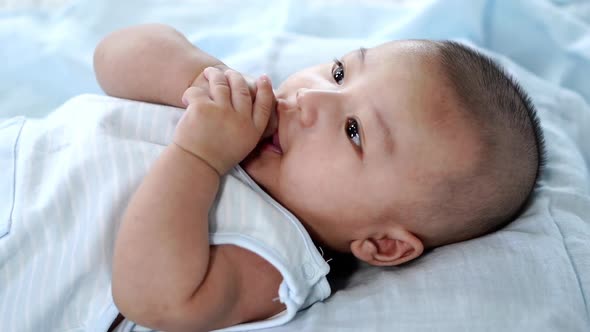 slow-motion of little baby with finger in mouth on a bed