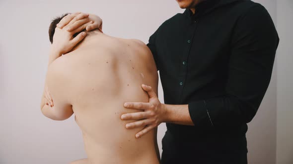 Young Man Having His Back Examined By a Doctor. Physiotheraphy and Back Pain Concept