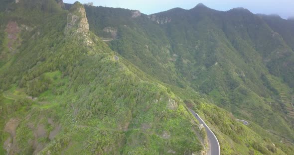 Aerial drone view of green mountains and road in Tenerife, Spain.