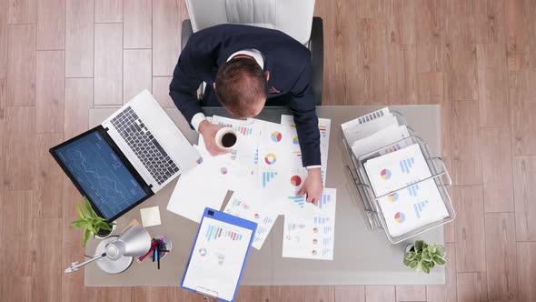 Top View of Focused Businessman in Suit Working on His Latop and Analysing Documents