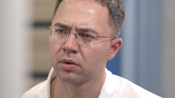 Serious Male Surgeon Controlling Surgery Looking at the Endoscope Monitor