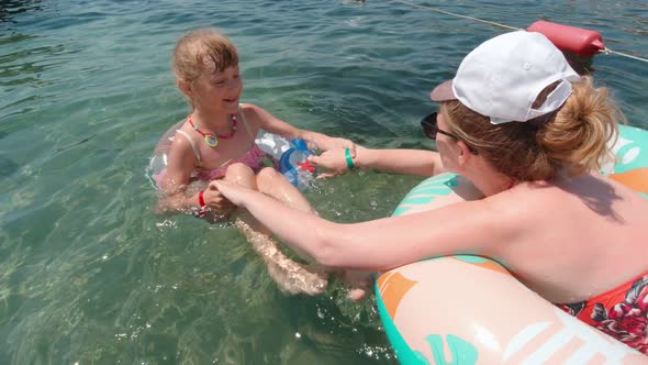 Woman With Daughter Swim In The Sea