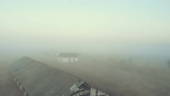 Abandoned Buildings on an Empty Field in the Fog