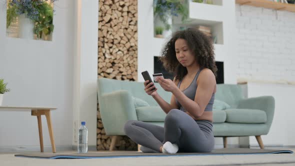 African Woman Making Online Payment on Smartphone on Yoga Mat