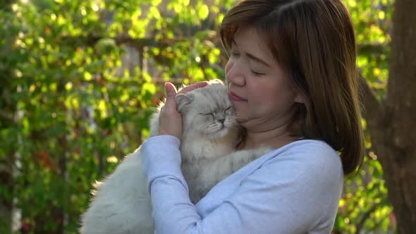 Asian Woman Holding Her Cat In The Light Of Sunset