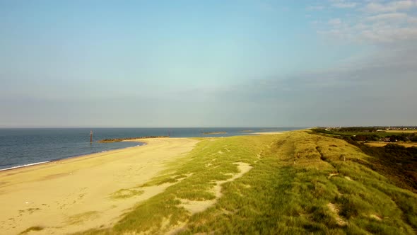 Drone flying over beautiful sand dunes and sea on a sunny beach, UK