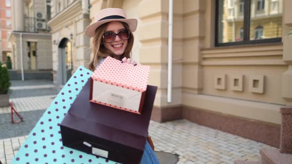 Young Woman with Shopping Bags Walking in a City at Summer Day