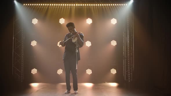 A Musician Plays the African Talking Drum Yuka in a Dark Studio Against the Backdrop of Lights. The