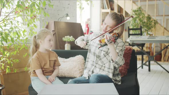 The Student Carefully Watches How the Teacher Plays the Violin