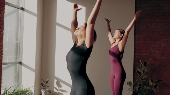 Two Young Girls in Sportswear Making Yoga Namaste Exercise in Yoga Studio