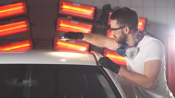 Man Checks Result of Polishing of Car with a Flashlight