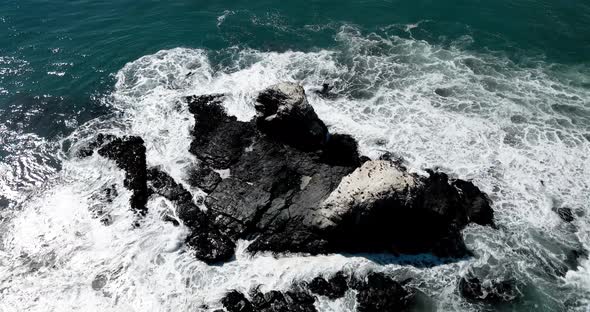 Aerial orbit of Punta de Lobos rocks with birds on their tops on a sunny day.