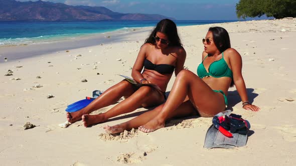 Female models happy and smiling on tranquil shore beach journey by turquoise ocean and bright sandy 