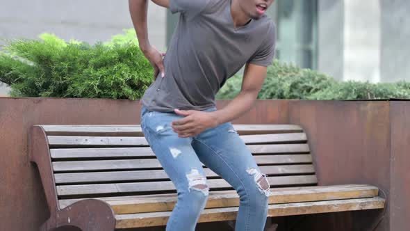 Young Young African Man Having Back Pain Sitting on Bench