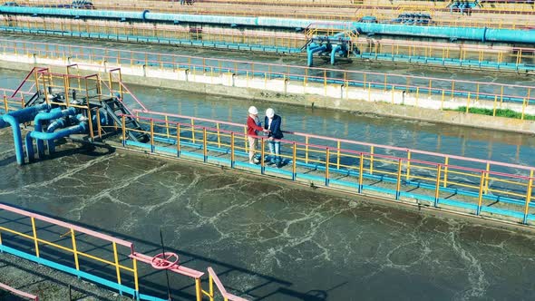 Two Specialists Discussing a Large Sewage Cleaning Facility