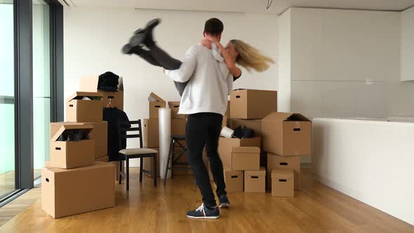 A Happy Moving Couple Is Excited About Moving Into a New Apartment - Piles of Cardboard Boxes