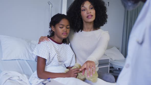 African american senior male doctor talking to african american mother and daughter at hospital