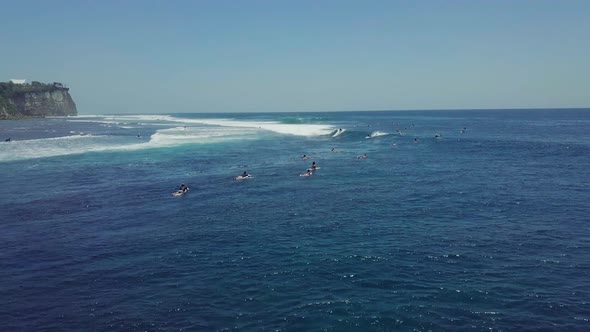 Drone View Over Blue Ocean Full of Surfers Enjoys Paddling and Riding Waves.
