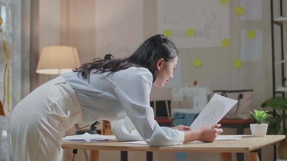 Woman Designer Positively Shaking His Head While Looking At Hand Bag Sketching On The Layout Bond