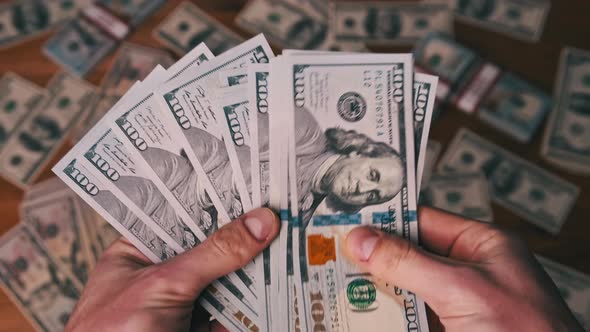 Dollars in Male Hands on Background of Table with Money Counting Banknotes