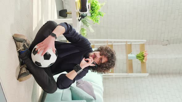 Man Standing with Soccer Ball in Hands and Talking on the Phone