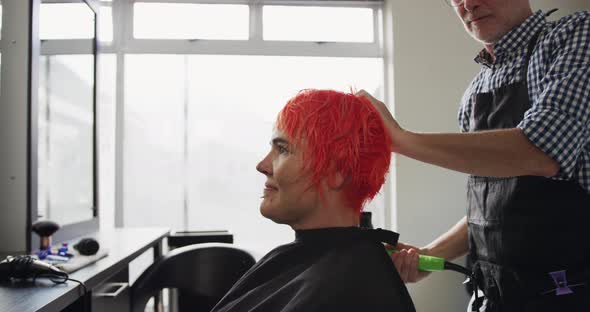 Side view woman having her hair dry by a hairdresser