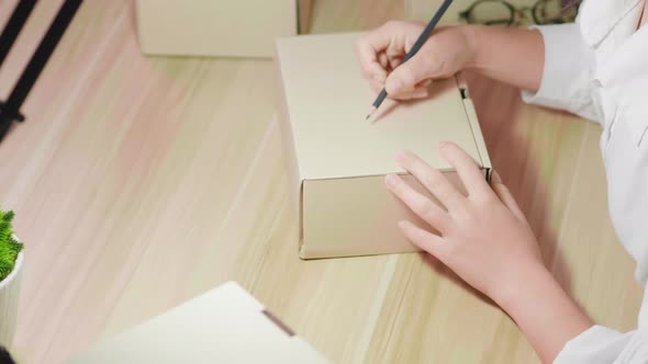 Close up hand of online seller are packing clothe orders on a box on the table