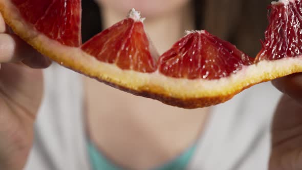 Woman Divides Fresh Grapefruit Biting Off Small Piece