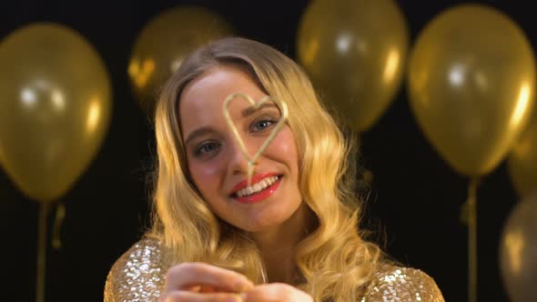 Nice Blond Woman Showing Heart-Shaped Bengal Light Into Camera, Celebration