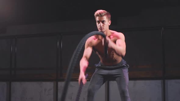 Athlete in Sweatpants Doing Cross Fit Workout with Battle Ropes on Sportive Show