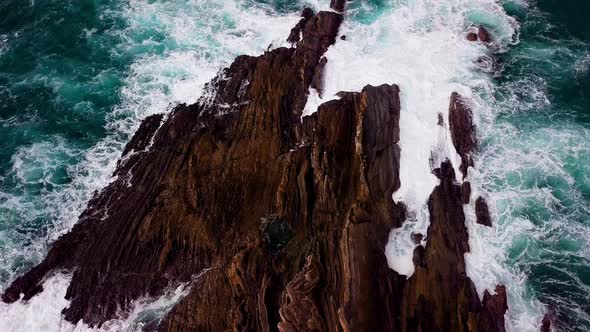 Turbulent Ocean Water flows onto Jagged Rock Formation in Big Sur Cali