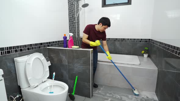 young man using brush to cleaning the tile in the bathroom