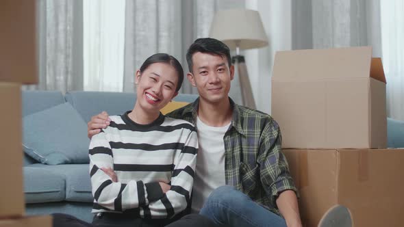Smiling Young Asian Couple, Man's Arm Around Woman'S Shoulder, Posing To The Camera In A New House