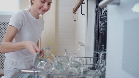 A Woman Opens the Dishwasher in Her Kitchen and Pulls Out Glasses