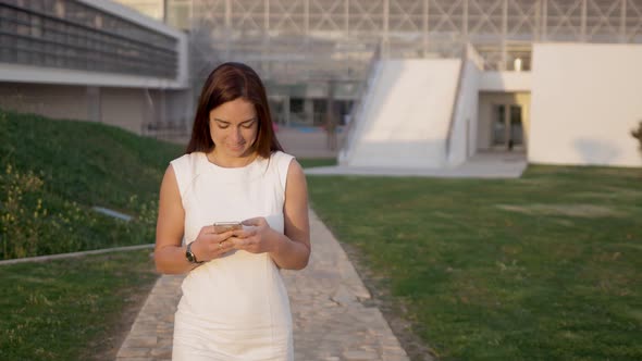 Front View of Happy Young Woman Messaging on Smartphone