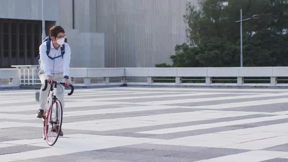 Asian man wearing face mask riding bicycle on the roof of corporate park