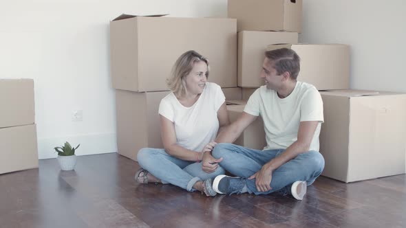 Cheerful Couple Sitting on Floor Near Heap of Boxes