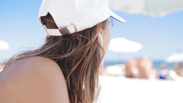 Closeup Portrait of a Beautiful Tanned Smiling Woman Is Lying on the Beach on a White Sand, Relaxing