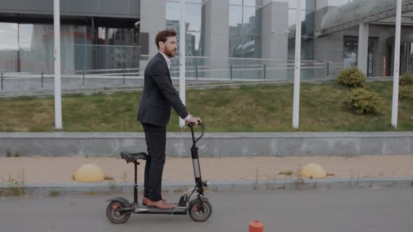 Young Modern Business Man in a Suit Riding an Electric Scooter