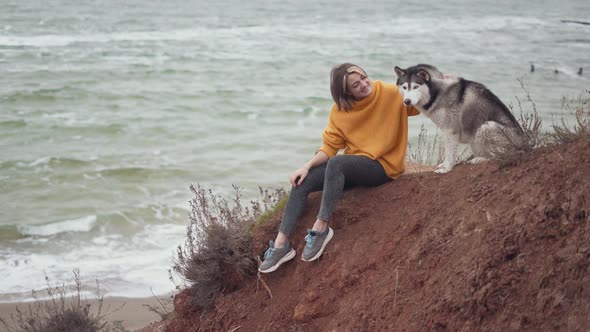 Young Beautiful Female Walking with Siberian Husky Dog on the Beach