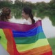 Asian Lesbian Couple With LGBT Flag Walking Together In The Park. - VideoHive Item for Sale