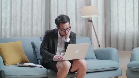 Asian Businessman In Jacket And Shorts Being Tired While Working With A Laptop At Home