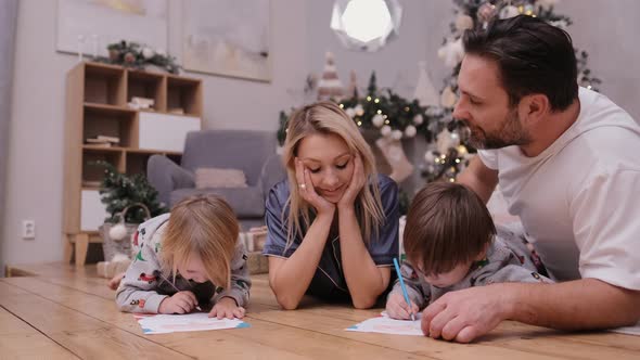 Happy Parents with Children Write Letters To Santa Claus Before Christmas