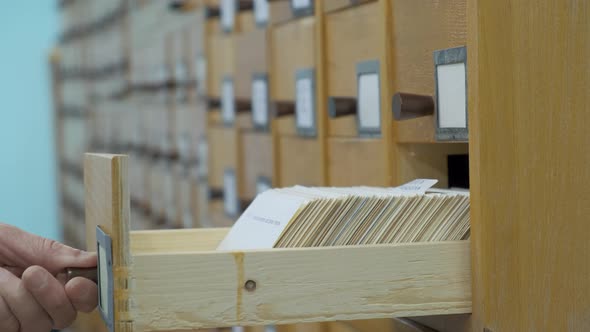 A Male Hand Searching Cards in Old Wooden Card Catalogue