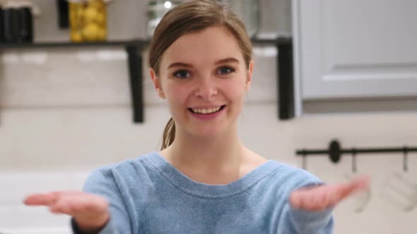 Inviting Gesture By Beautiful Young Woman Sitting on Chair at Home