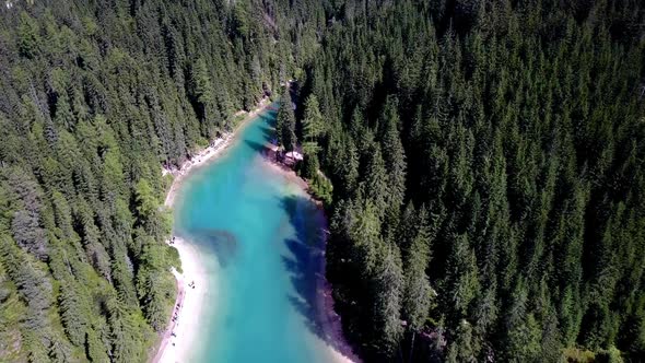 Lake Braies northern tip in the Italian Dolomites with people walking on the shore, Aerial lowering