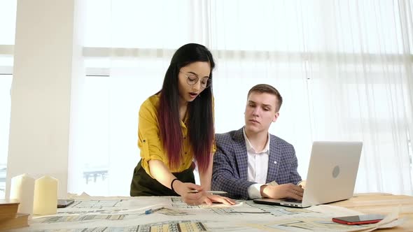 Young creative designers in bright office with large windows brainstorm.