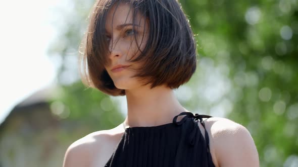 Girl With Short Haircut Posing With Green Trees At The Background