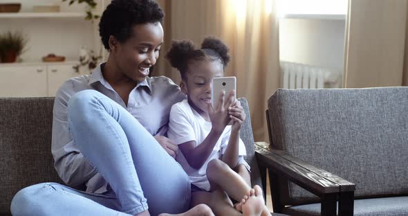 Young Mom with Short Afro Hairstyle Hugs Little Daughter Curious Mixed Race Child Black Girl Woman