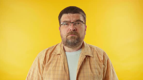 Caucasian bearded man in yellow shirt confidently saying no on camera over colorful background